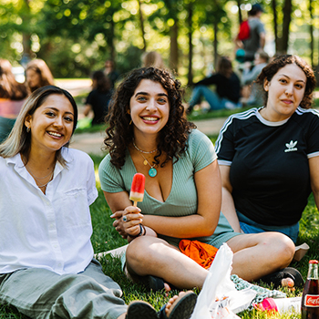 three students sitting on the Quad with popsicles