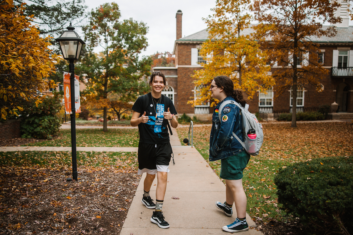 Two students smiling with thumbs up