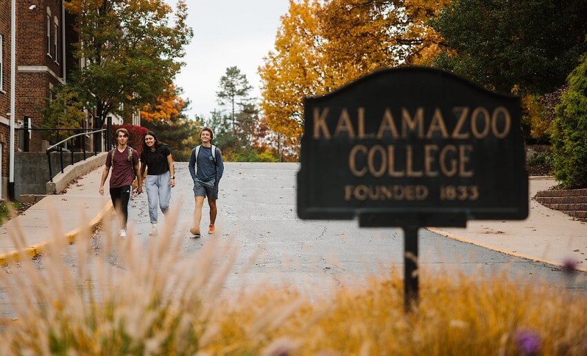 Students walking near Kalamazoo College Sign
