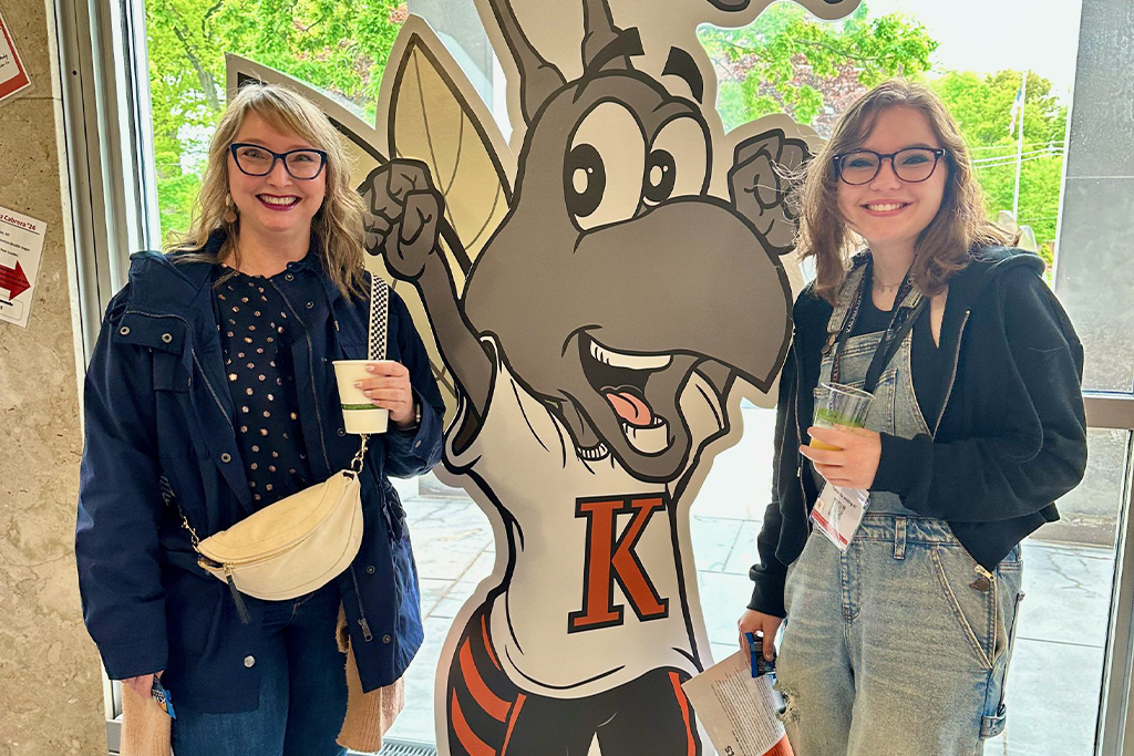 A parent and prospective student with full sized Buzz cutout